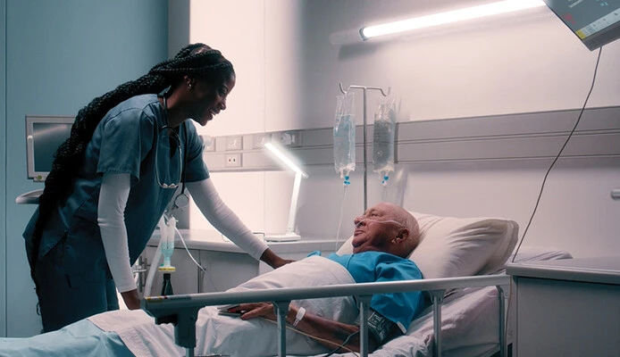 nurse talks to patient in hospital bed