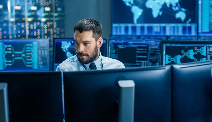 man surrounded by monitors with security data