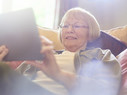 senior woman smiling as she uses her digital tablet