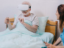 Nurse sitting by patient using VR headset