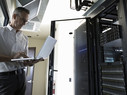 Male Caucasian IT technician using laptop in server room