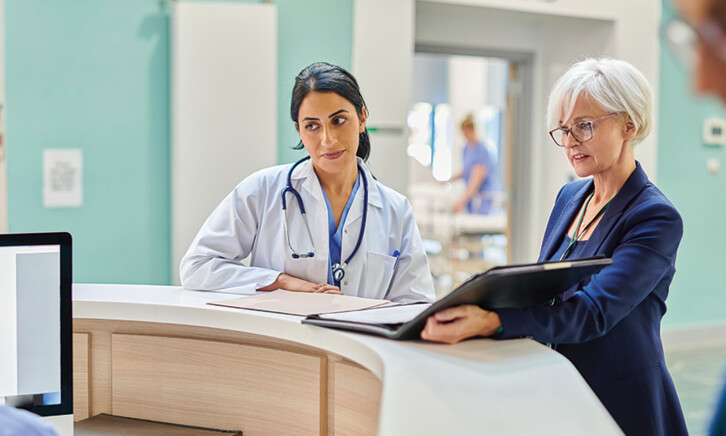 clinicians and administrators collaborate at hospital desk