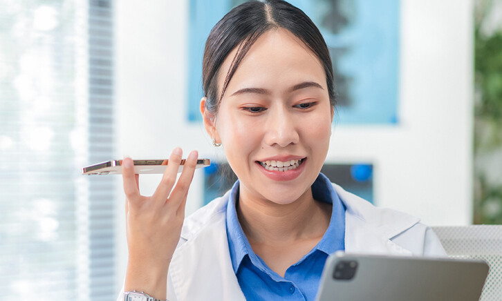 Doctor using phone to dictate to tablet