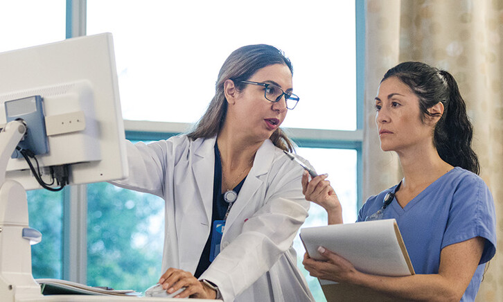 doctor shows intern AI features in an EHR on computer