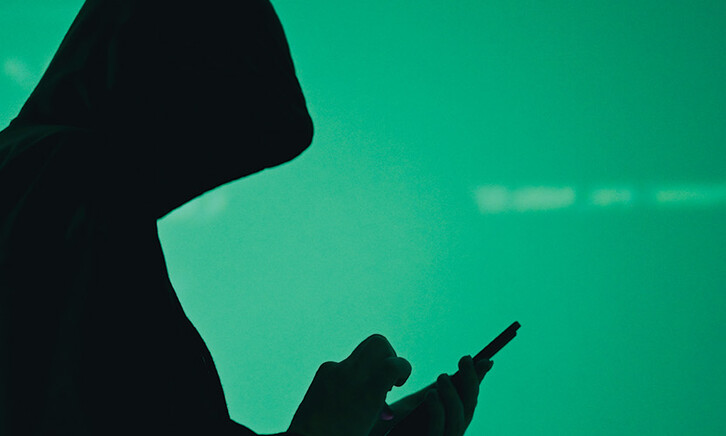 silhouette of hooded figure on phone