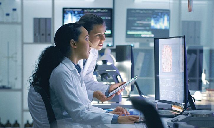 two researchers look at medical data on computer in lab