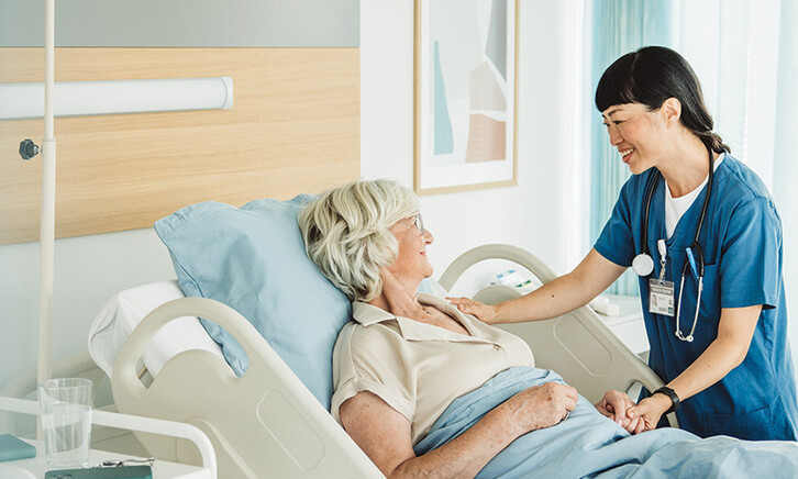 nurse cares for senior in hospital bed