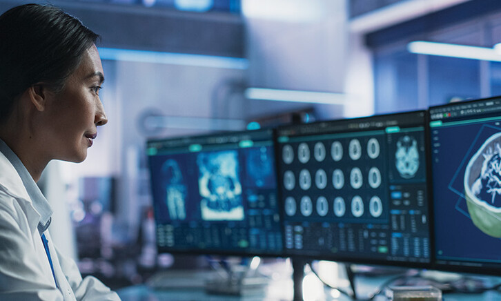 healthcare researcher looks at images and data on monitors