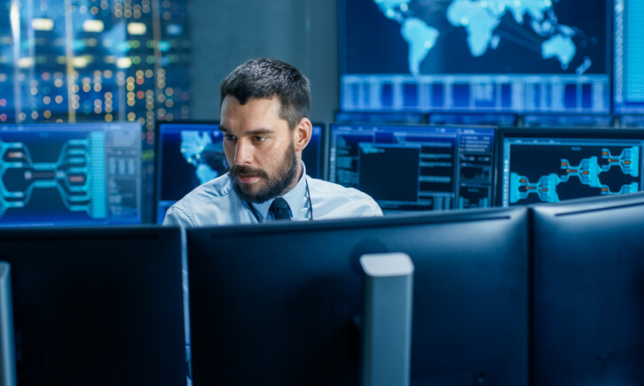 man surrounded by monitors with security data