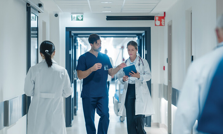 clinicians walk down busy hospital hallway
