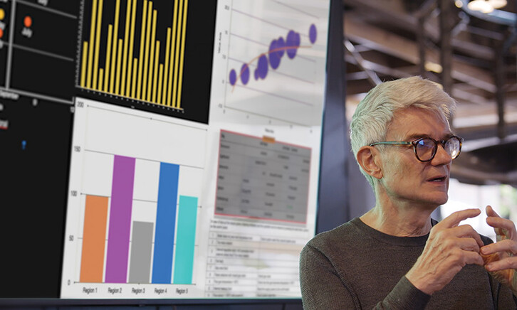 man gives presentation in front of screen with charts