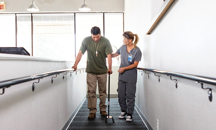 nurse helps veteran walk for rehab