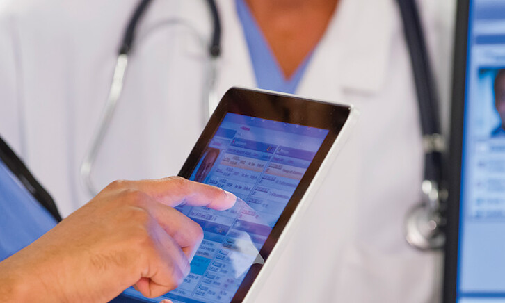 nurse and doctor look at EHR on tablet and monitor