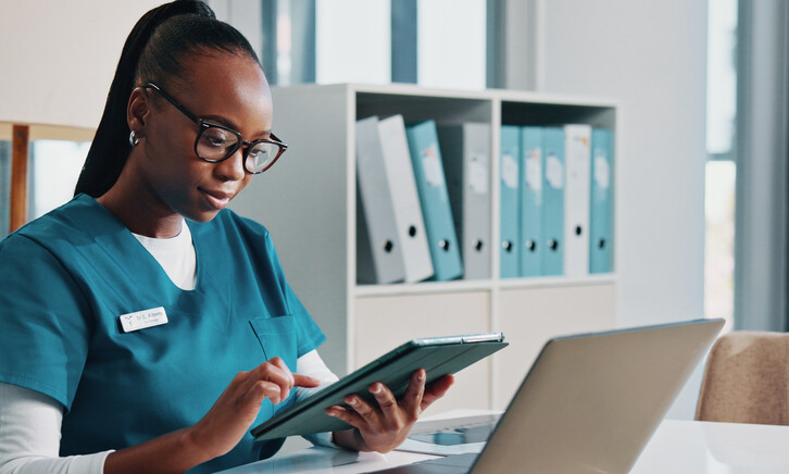 nurse using tablet and laptop at desk