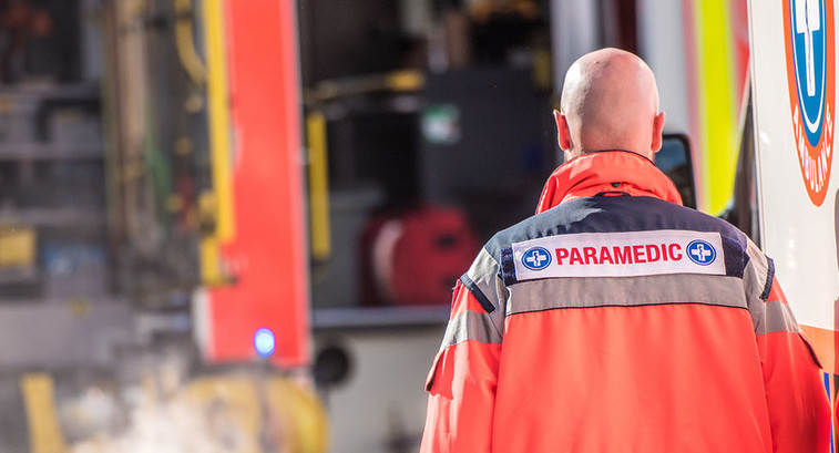 Rear view of male paramedic walking outside ambulance.