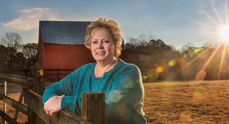 Melissa Hall on farm with barn and sunset in the background