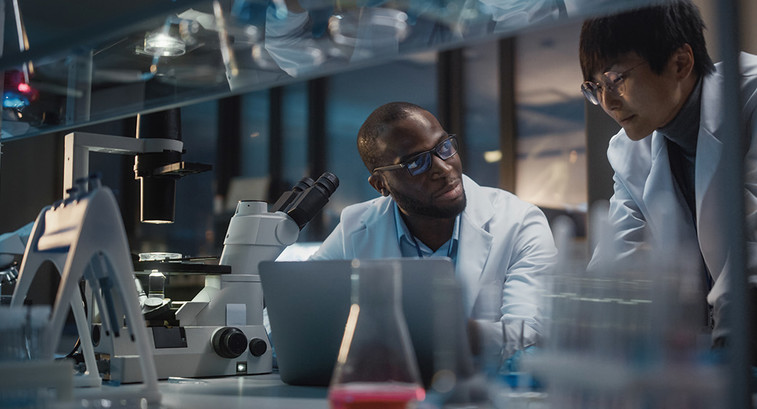 two scientists look at data on laptop in a lab