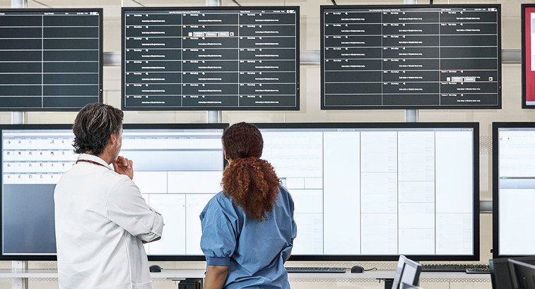 Nurse and doctor consider information on multiple screens
