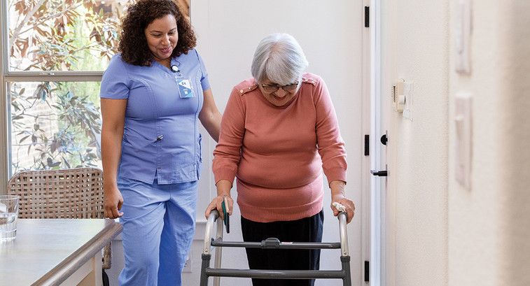 nurse helps patient with walker at home