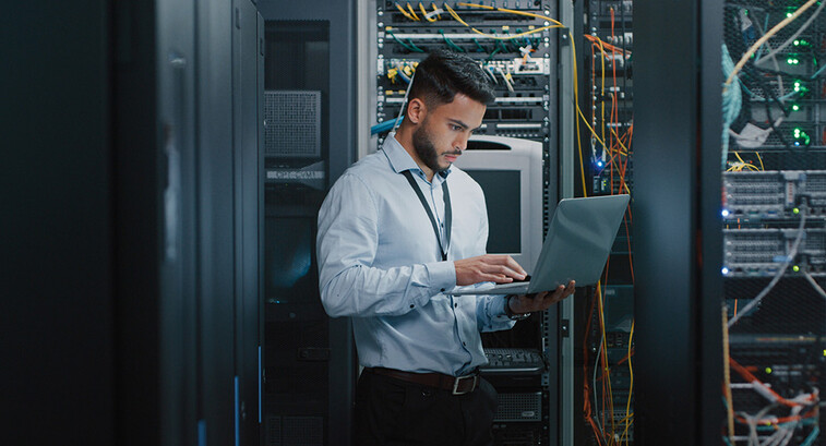 man on laptop in server room