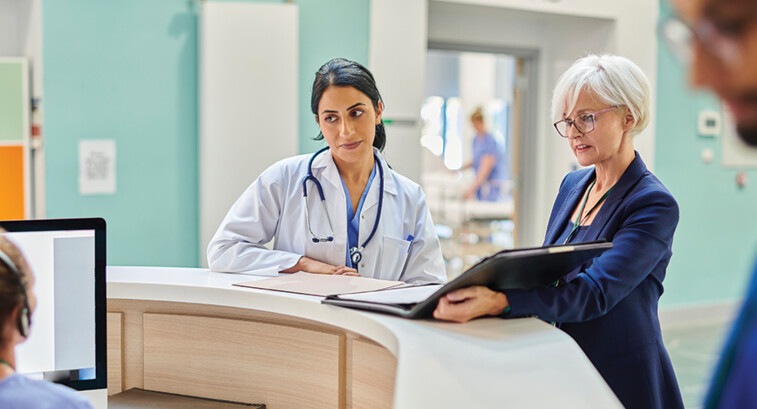 clinicians and administrators collaborate at hospital desk