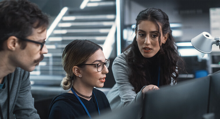 cybersecurity team members talk in front of monitors