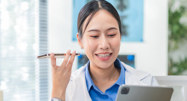 Doctor using phone to dictate to tablet