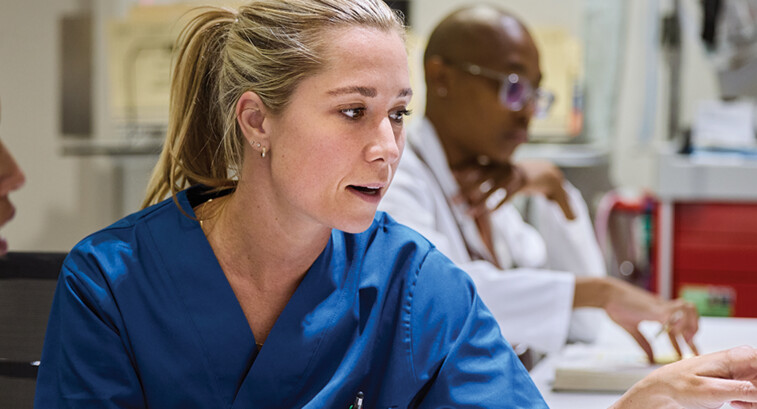 nurses talk in front of desktop computer