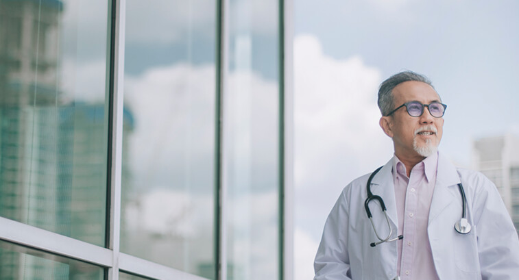 doctor in front of clouds and reflective building