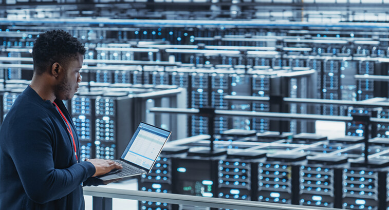 engineer with laptop overlooking data center