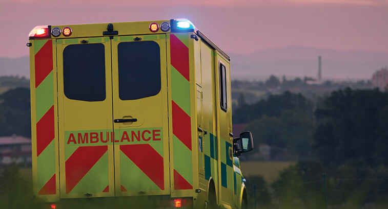 ambulance driving down country road at sunset