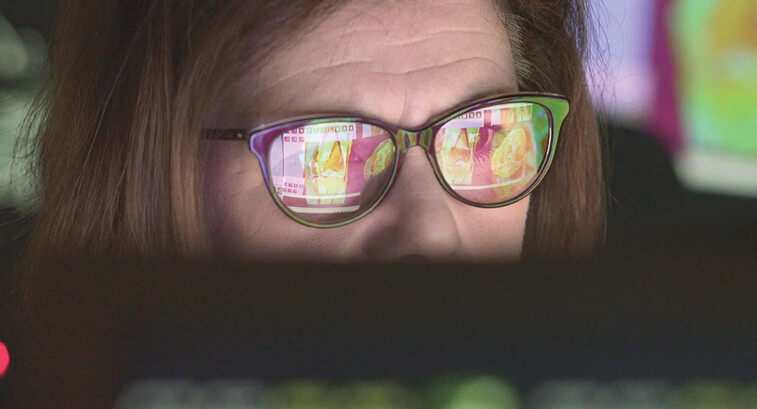 woman wearing glasses looking at healthcare data on screen