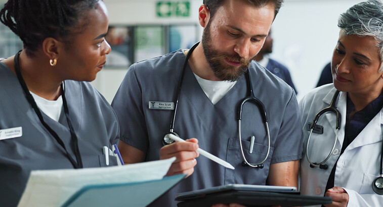 Team of clinicians talk over tablet