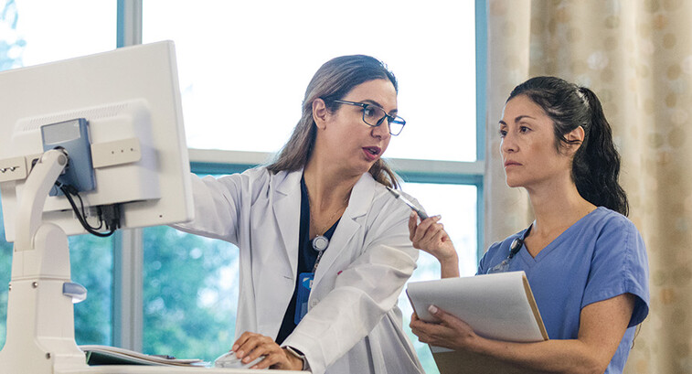 doctor shows intern AI features in an EHR on computer