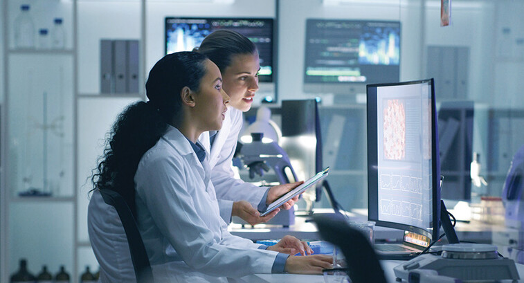 two researchers look at medical data on computer in lab