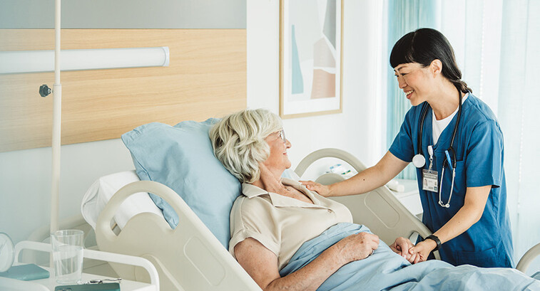 nurse cares for senior in hospital bed