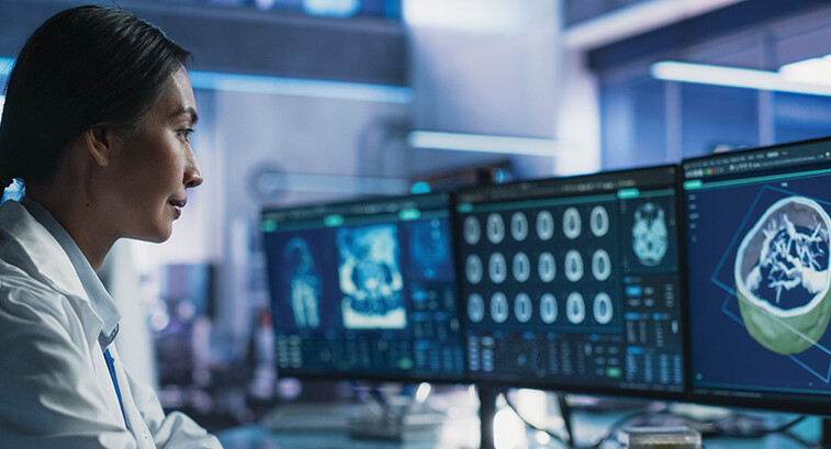 healthcare researcher looks at images and data on monitors