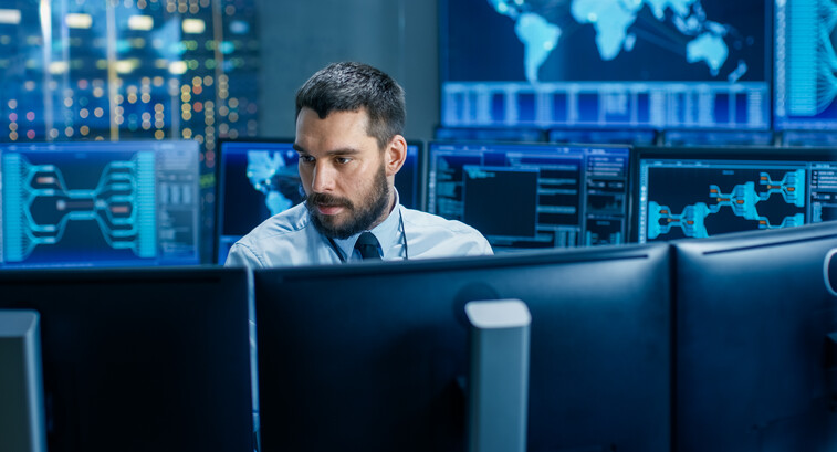 man surrounded by monitors with security data