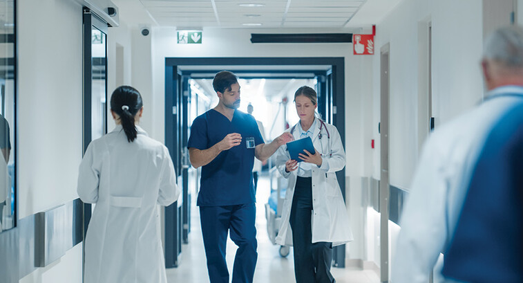 clinicians walk down busy hospital hallway