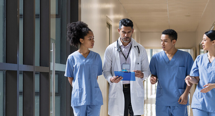 Doctor holding clipboard walks with medical students