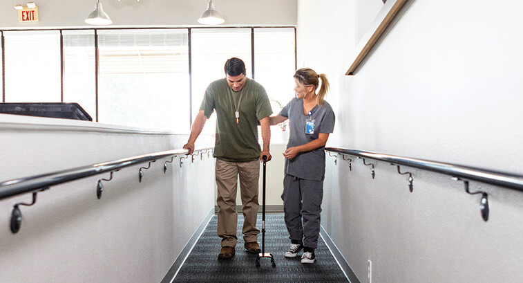 nurse helps veteran walk for rehab