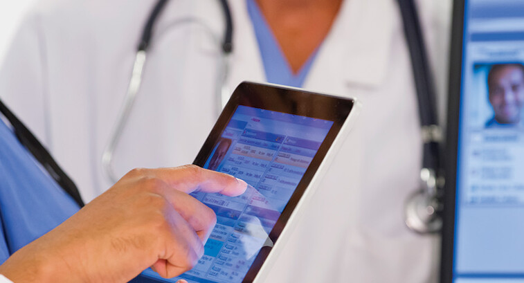 nurse and doctor look at EHR on tablet and monitor