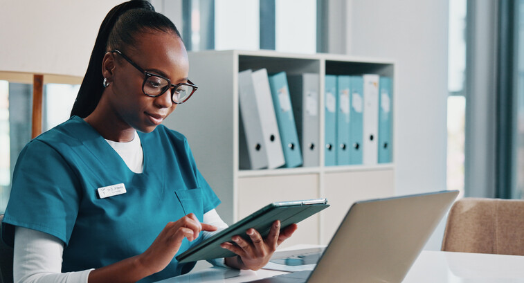 nurse using tablet and laptop at desk