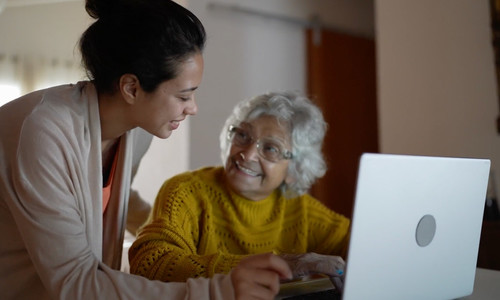 Nurse helps senior woman with laptop