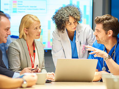 Doctors and business teams collaborating around computer
