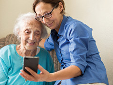 women helps elderly women make video call on phone