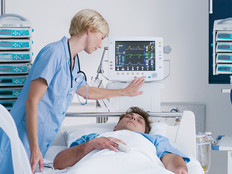 nurse checks on patient in hospital bed surrounded by IoMT devices