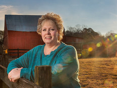Melissa Hall on farm with barn and sunset in the background