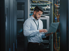 man on laptop in server room