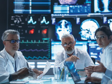 group of doctors talk amid large screens